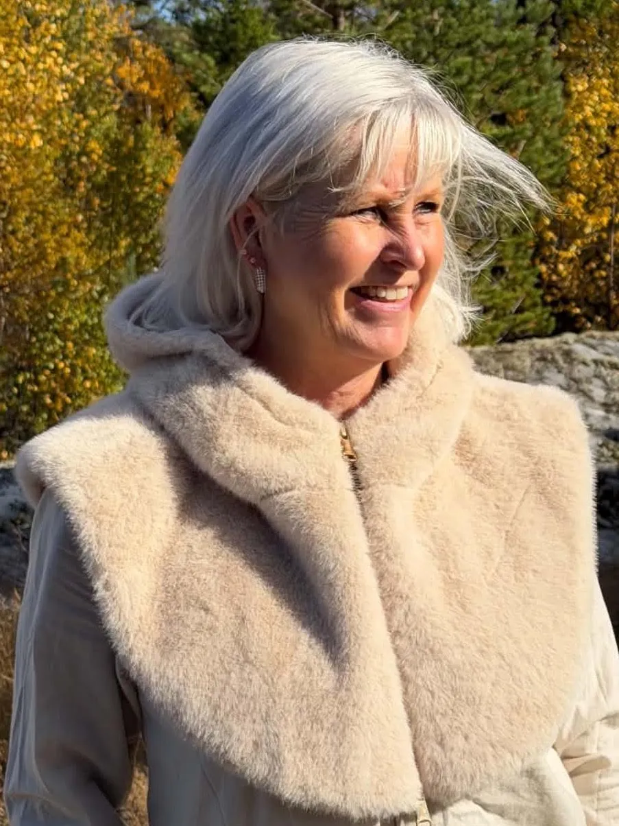 Kvinne i kremfarget ponchosjal med pelskant